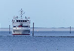 Die Fähre, ein weißes Schiff, mit dem Bug zum Betrachter in einem Priel im Wattenmeer vor Wangerooge.