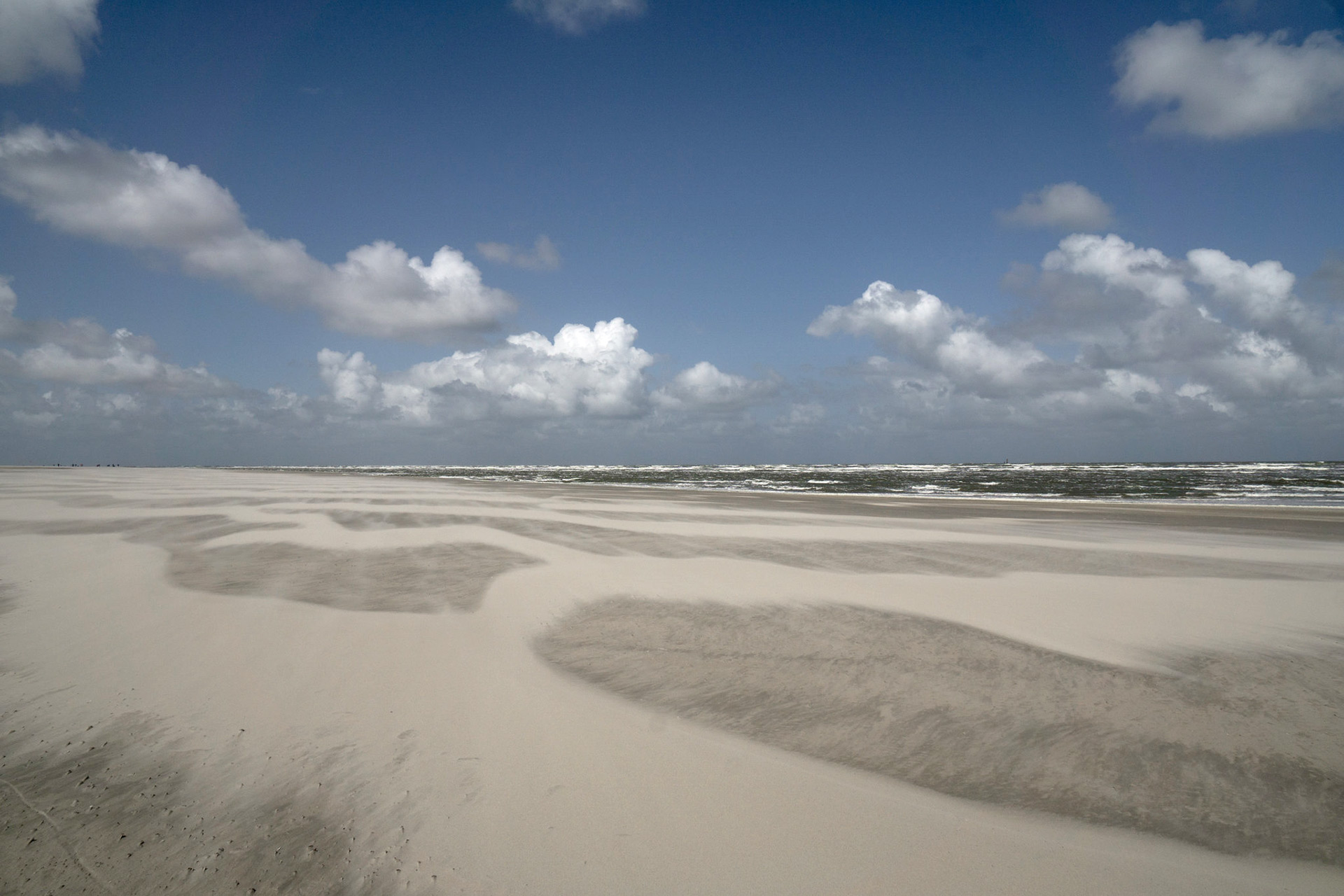 Ein sonniger, kalter Tag am Strand von Wangerooge. Der Sand ist verweht, das Mehr ist rau.